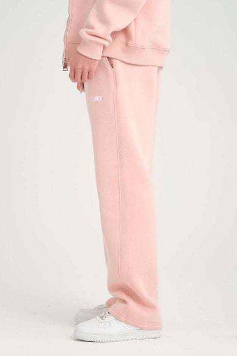 2. Side view of pink jogger pants with DALER logo, worn with white sneakers