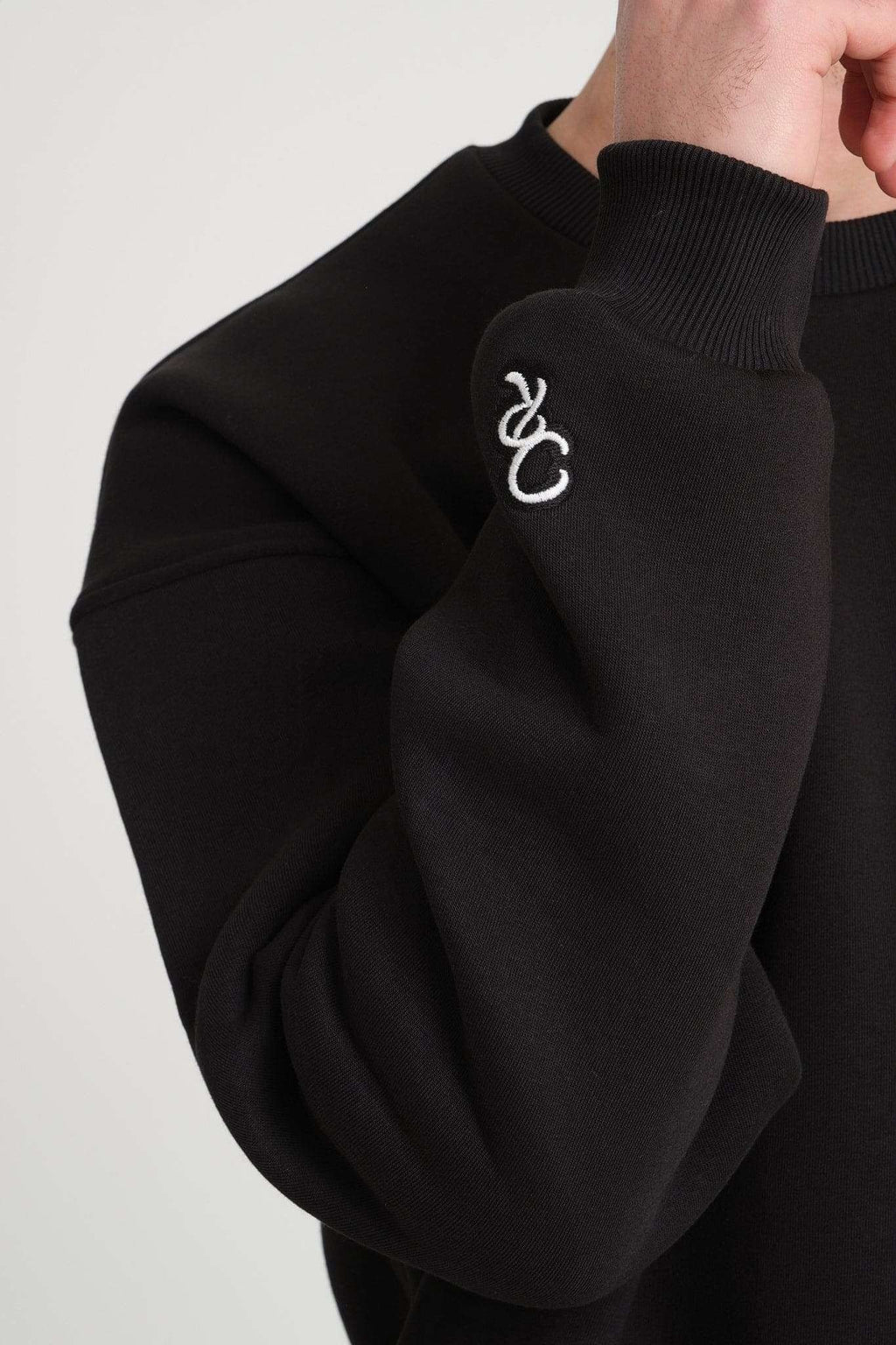 3. Close-up of sleeve embroidery on black DalerClo sweatshirt showing distinctive design