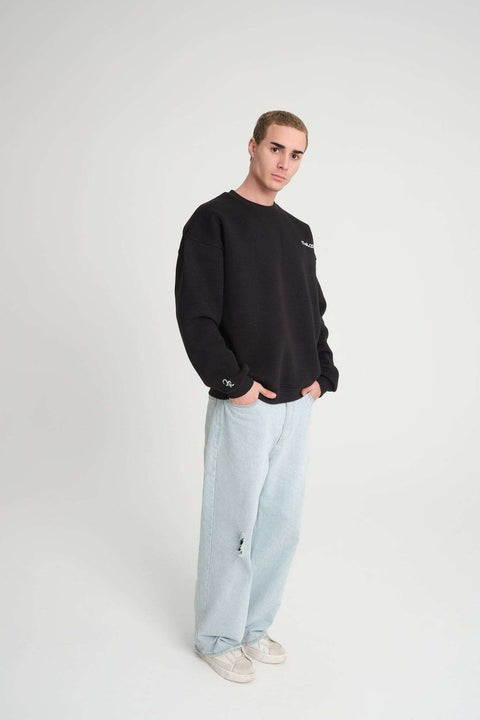 1. Man in black oversized DalerClo sweatshirt and light jeans standing in studio setting