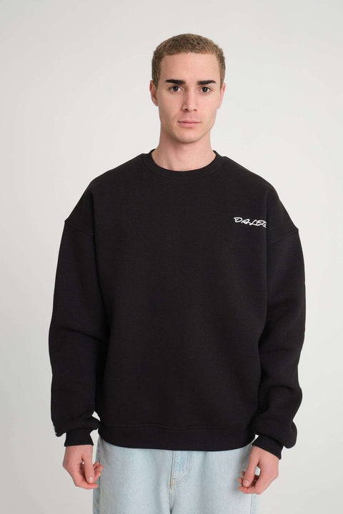 1. Man wearing black oversized DalerClo sweatshirt with chest embroidery, standing against a plain background