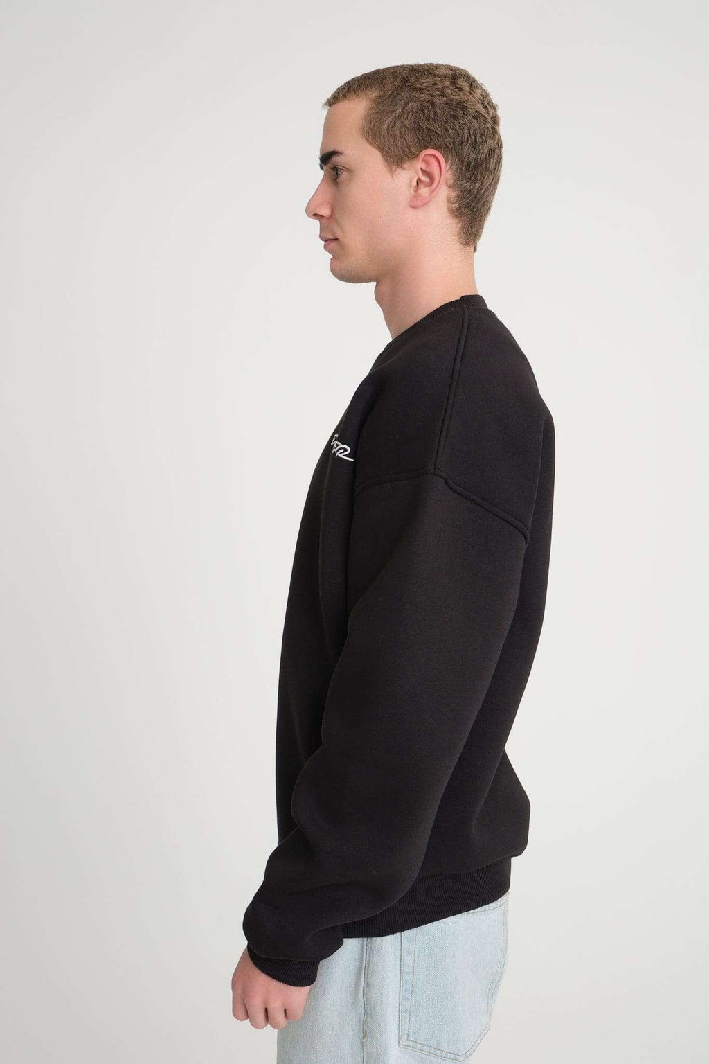 2. Side view of man wearing black oversized DalerClo sweatshirt highlighting relaxed fit