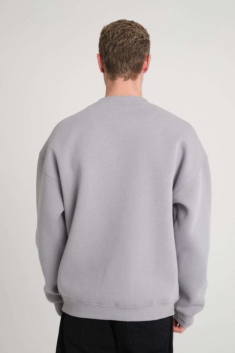 2. Back view of man wearing grey oversized DalerClo sweatshirt in studio setting