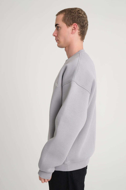 2. Side view of man wearing grey oversized DalerClo sweatshirt in studio setting