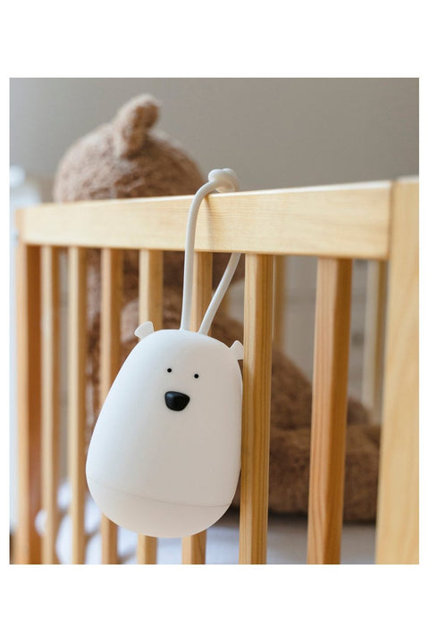 1. White bear-shaped night light hanging on a wooden crib with a teddy bear in the background
