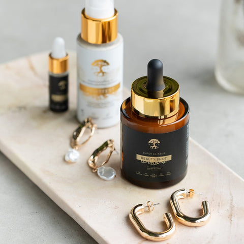 3. HOIA homespa Beauty SHOT Serum 30ml with dropper, small bottle, and additional skincare product, styled with gold earrings on marble surface