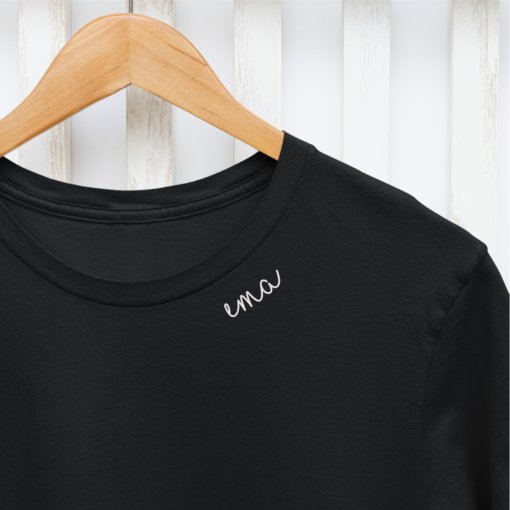 6. Close-up of white embroidered collar on organic cotton t-shirt with 'ema' text