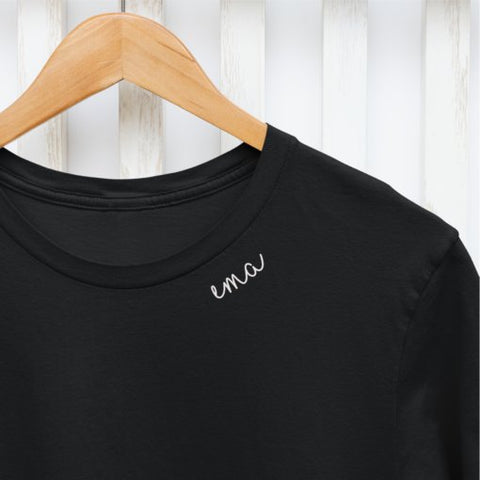6. Close-up of white embroidered collar on organic cotton t-shirt with 'ema' text