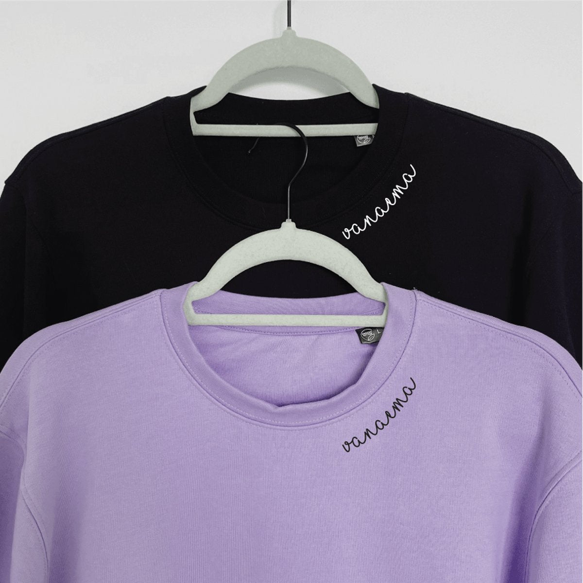 3. Black and lilac Beebila 'Vanaema' sweatshirts with embroidered collars on hangers, studio setting