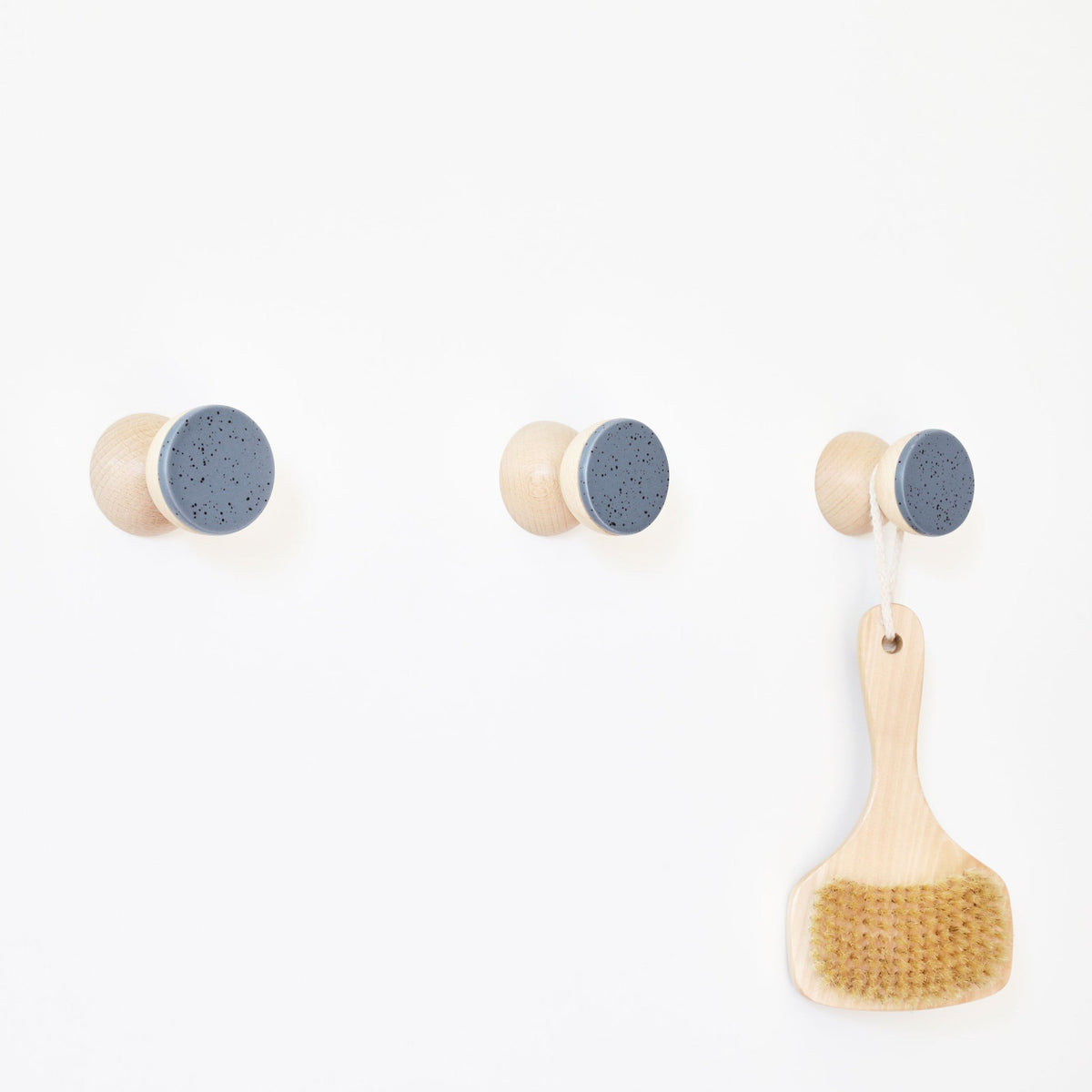 2. Beech Wood & Ceramic Wall Hooks with blue black specks, shown with a hanging brush