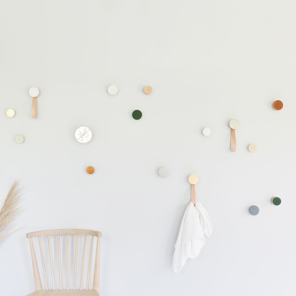 2. Lifestyle image of Beech Wood & Ceramic Wall Hooks by 5mm Paper in a creative space, featuring various colors including dark terracotta orange, used for hanging items