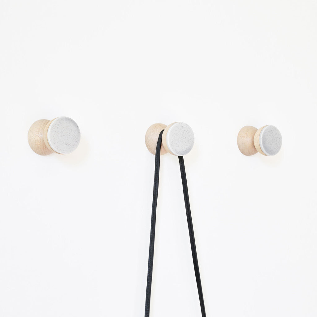 3. Studio shot of three 5mm Paper Beech Wood & Ceramic Wall Hooks in grey sand, showing functionality