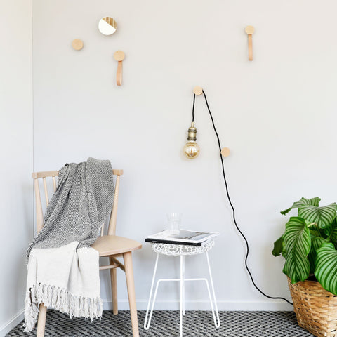 3. Lifestyle image of beech wood wall hooks by 5mm Paper in a living space with hooks used for hanging a lamp and decor