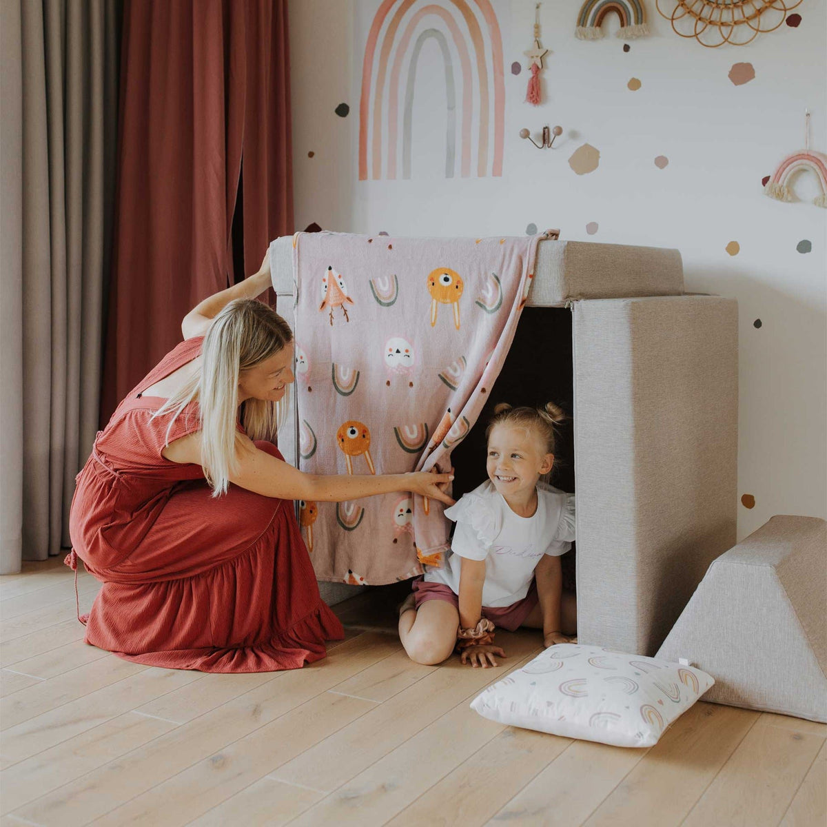 6. Woman and child playing with beige Monboxy play mattress set covered with a colorful blanket
