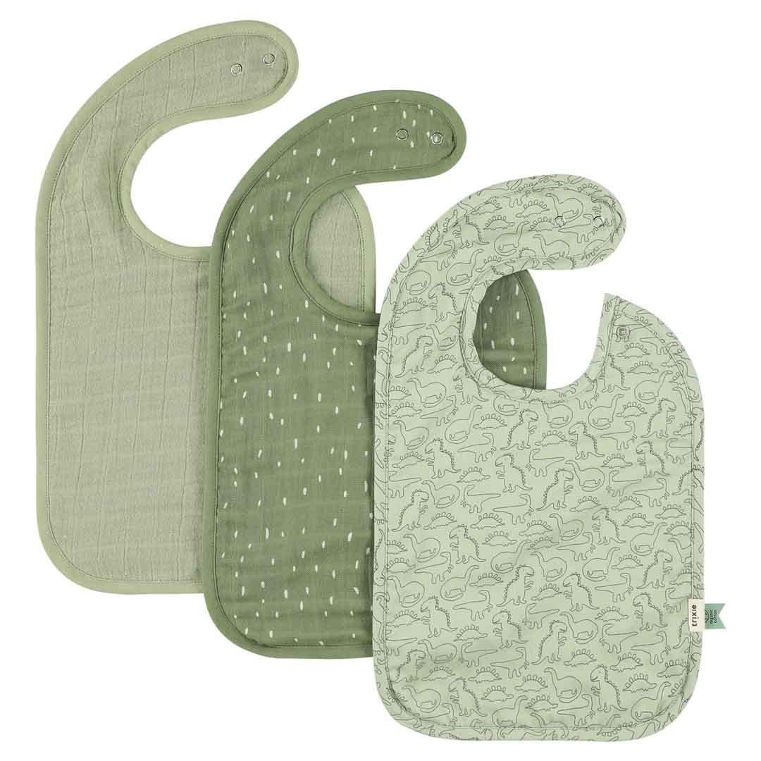 1. Set of three Trixie Baby bibs in green shades, featuring one with dinosaur pattern and two solid muslin bibs, displayed on a white background