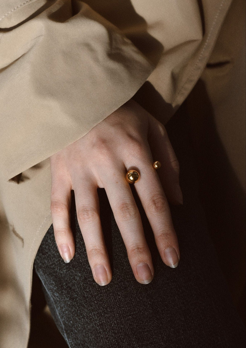 7. Close-up of woman's hand wearing NO MORE Big Bomb Multisize Ring in gold, styled with a beige coat