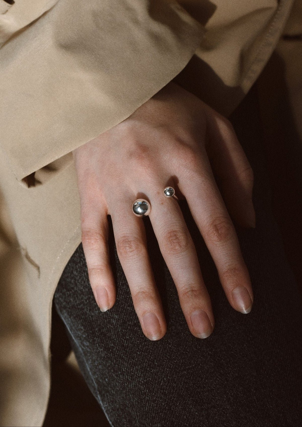 5. NO MORE Big Bomb Multisize Ring in silver on woman's hand, styled with a beige coat, highlighting minimalist elegance