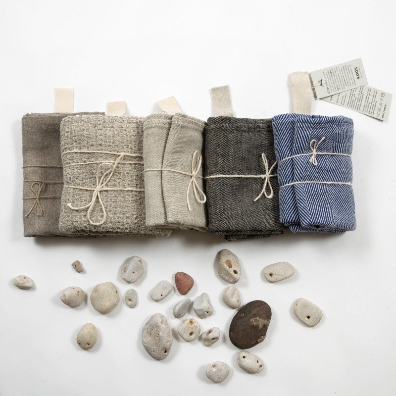 8. Collection of folded linen towels in various colors with stones on white background