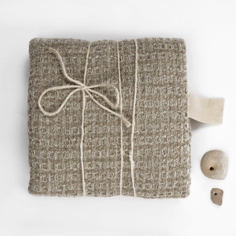 9. Folded grey textured linen towel with string tie and stones on white background