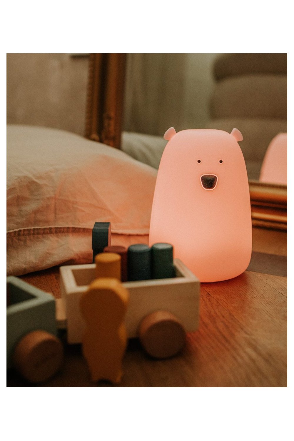 2. Pink teddy bear-shaped lamp on wooden floor next to toy train, warm lighting