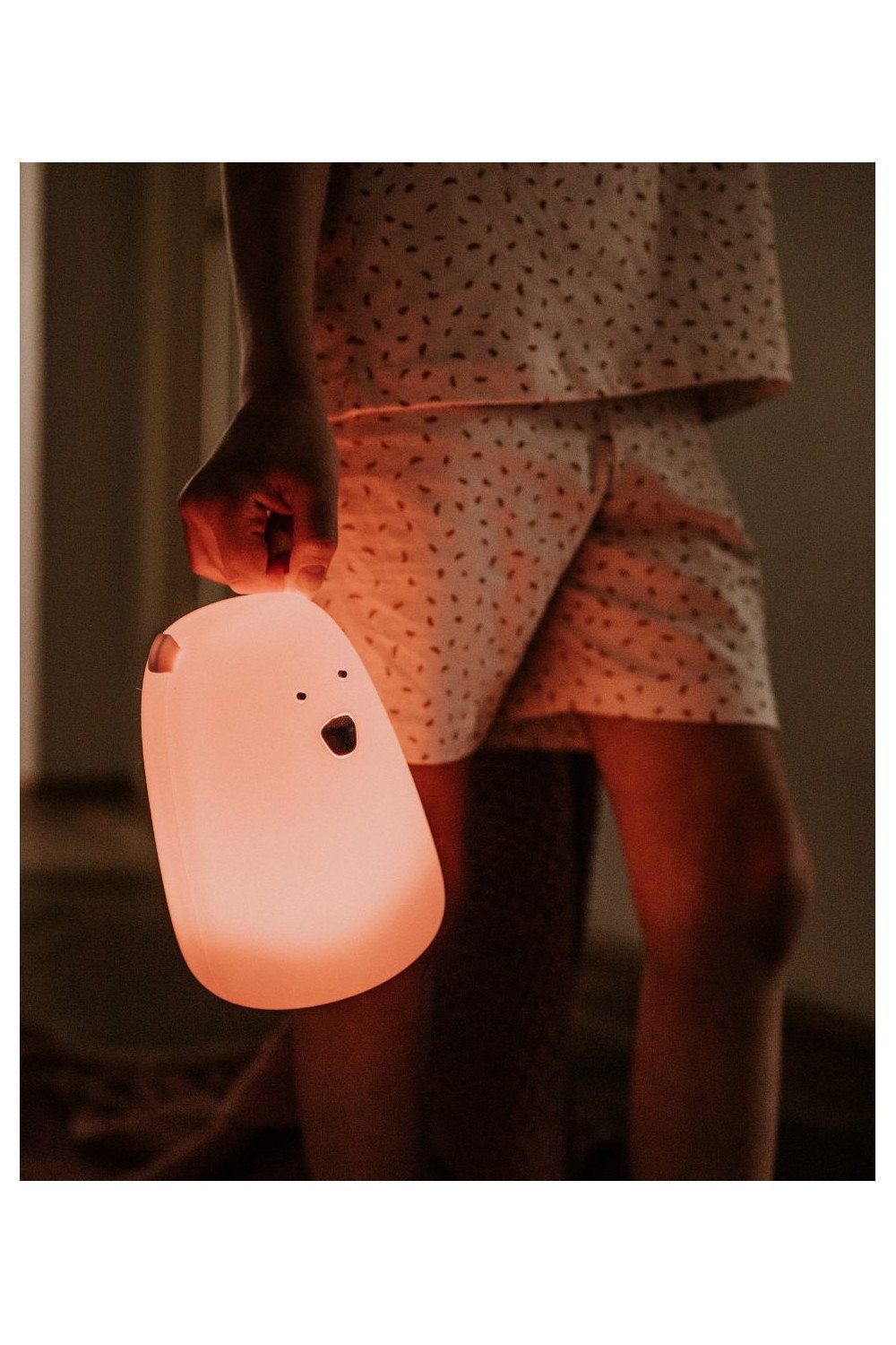 4. Child holding pink teddy bear-shaped lamp, wearing pajamas, warm lighting