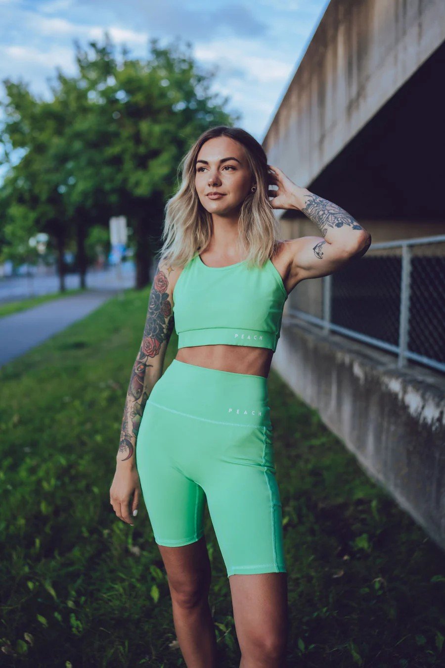 1. Woman wearing Peachlabel green biker shorts and matching top, standing outdoors