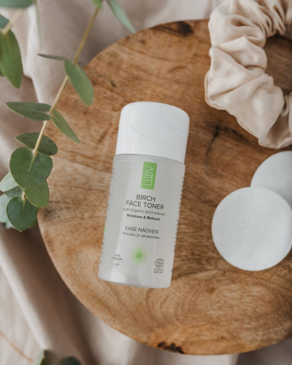3. LUUV Birch Face Toner bottle on wooden surface with eucalyptus leaves and cotton pads