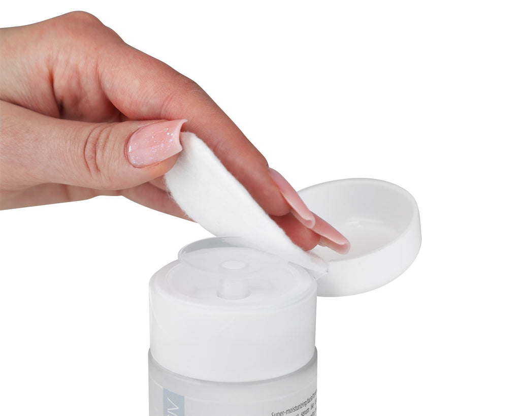 2. Hand holding a cotton pad above the open cap of LUUV Birch Face Toner bottle