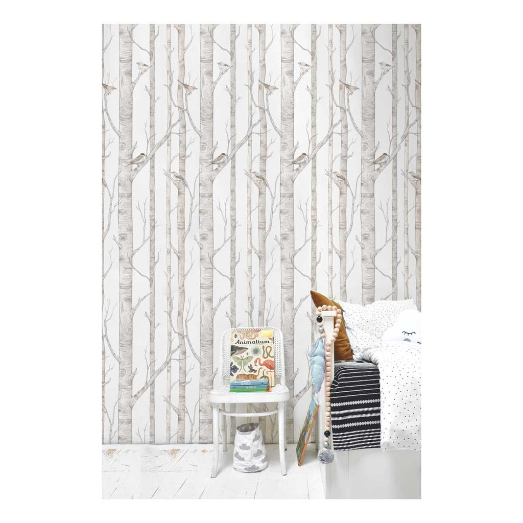 2. Birch forest wallpaper in a child's bedroom with birch trees and birds, next to a white side table with books and a bed with patterned pillows