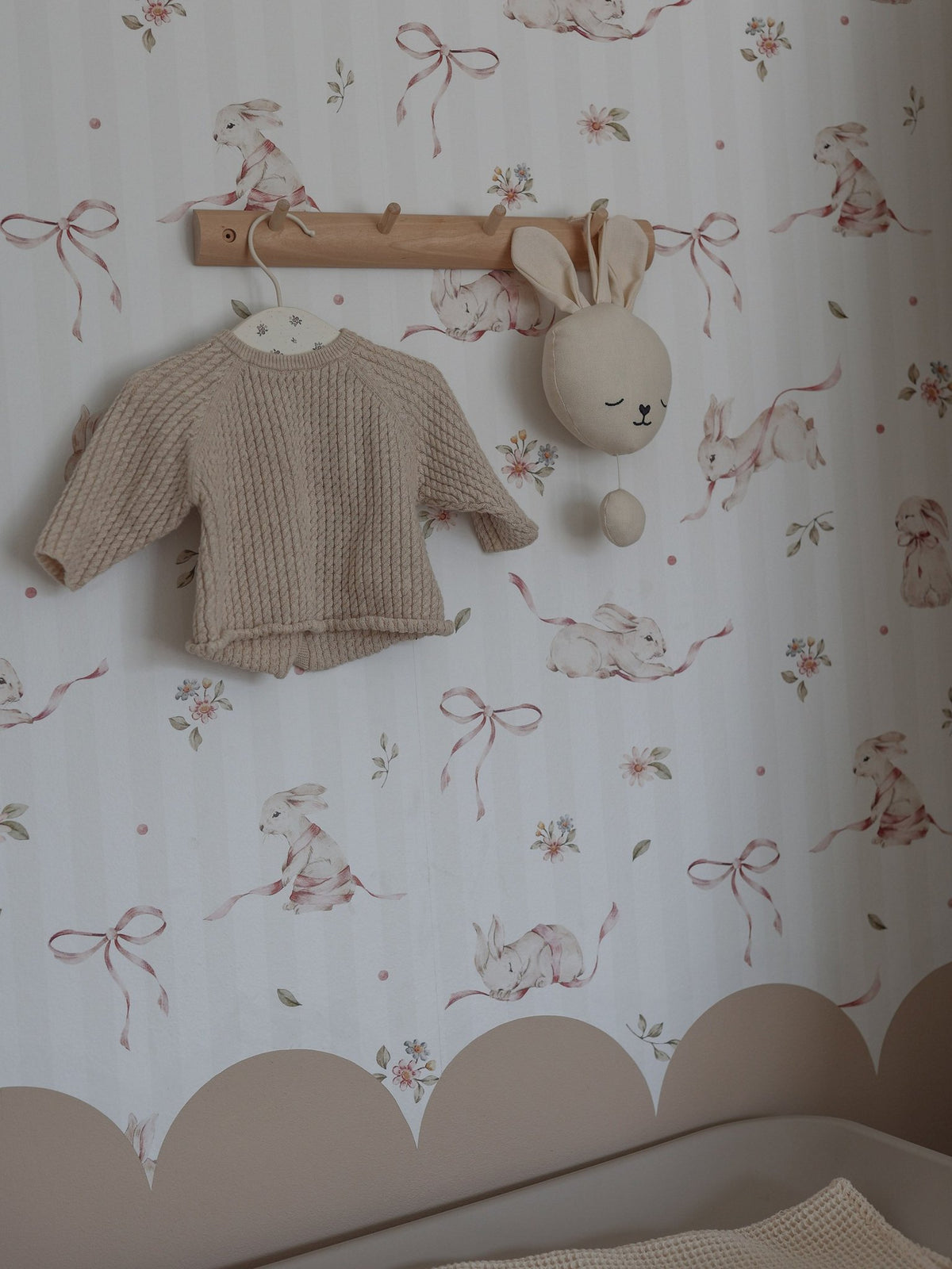 1. Children's room with pink rabbits on stripes wallpaper, beige knit sweater, and bunny decor
