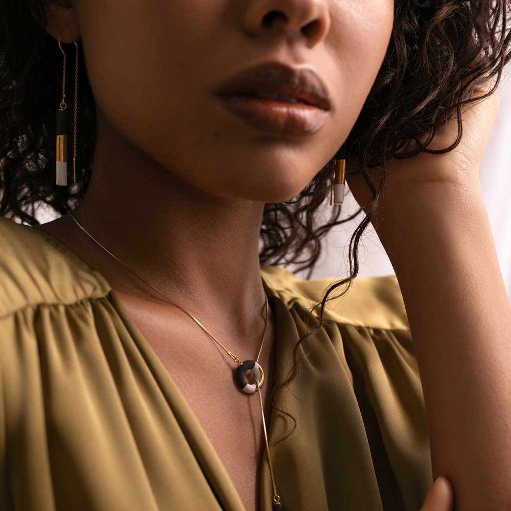 1. Woman wearing SCULP OM Choker B&W with ceramic pendant and gold-over-sterling silver chain, styled with matching earrings