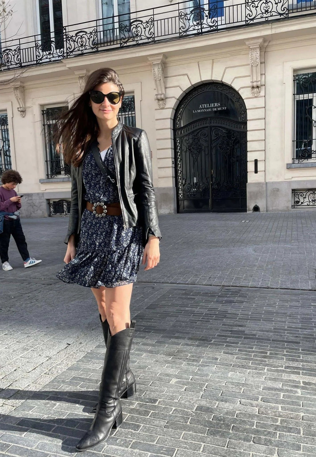 1. Woman in black knee-high leather boots with block heel and floral dress walking on city street