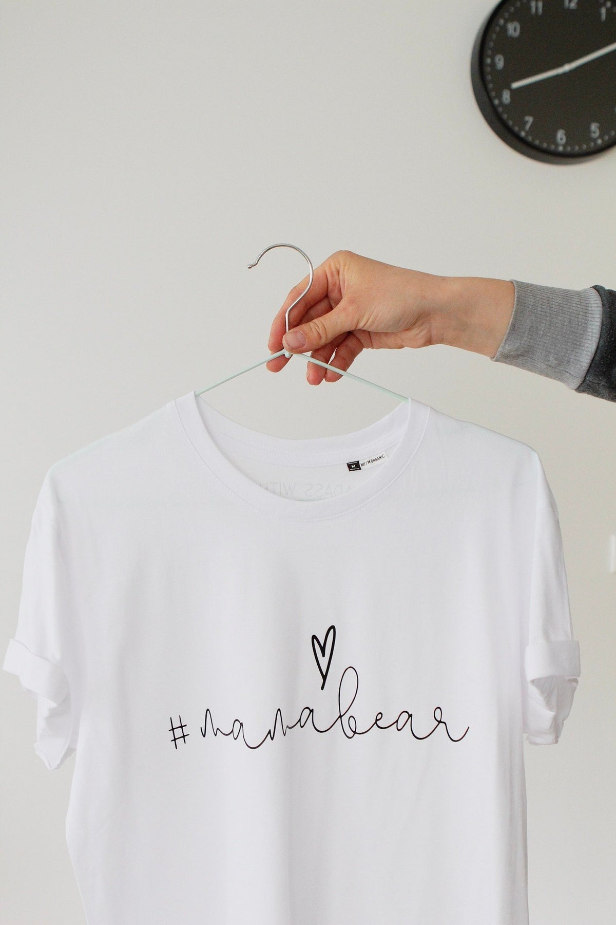 3. Close-up of white Mamabear T-shirt by Black Giraffe Brand with rolled-up sleeves, shown on hanger