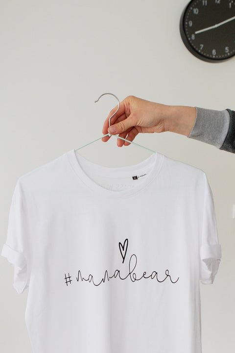 3. Close-up of white Mamabear T-shirt by Black Giraffe Brand with rolled-up sleeves, shown on hanger