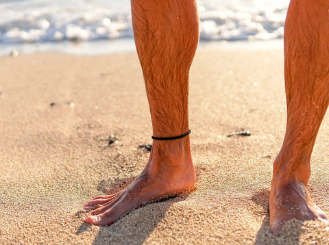 1. Men's Black Lava Anklet by Canary Lava worn on beach, showcasing rugged elegance and natural sophistication