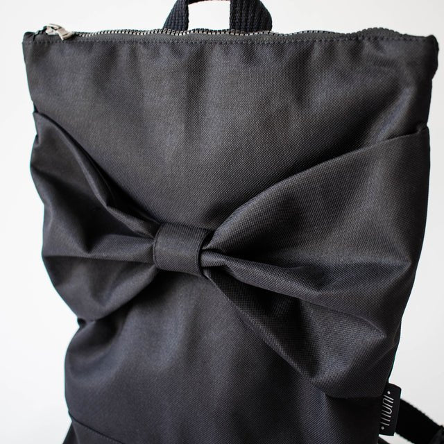 8. Close-up of Muni Black Bow backpack, highlighting bow detail and waterproof polyester fabric