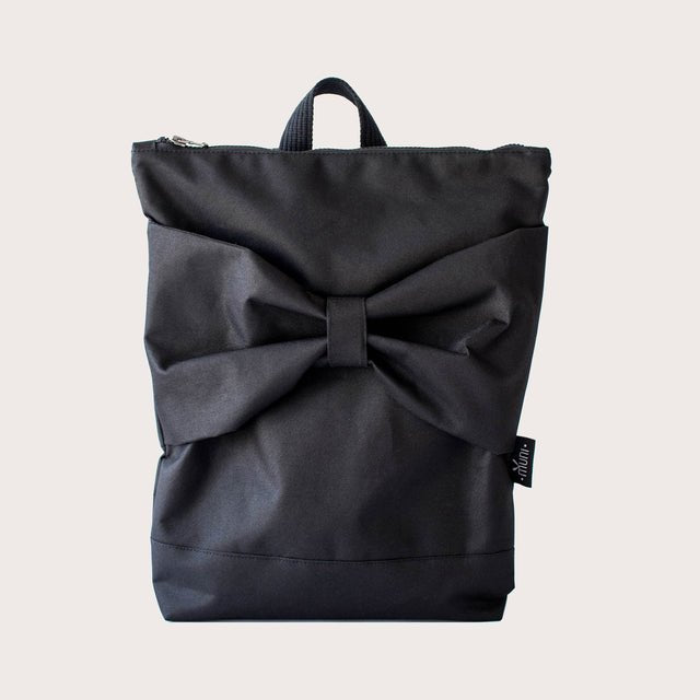 7. Front view of Muni Black Bow backpack in studio, showcasing elegant bow design and zipper closure