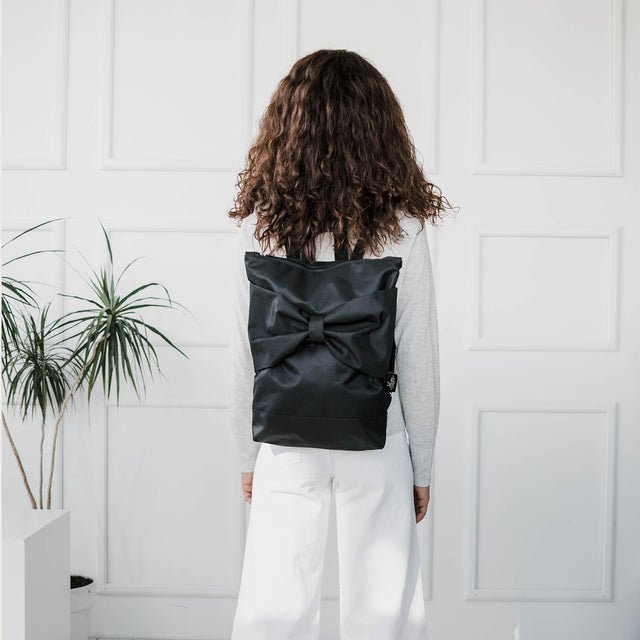5. Back view of woman with Muni Black Bow backpack, highlighting sleek design and comfort