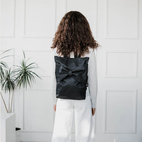 5. Back view of woman with Muni Black Bow backpack, highlighting sleek design and comfort