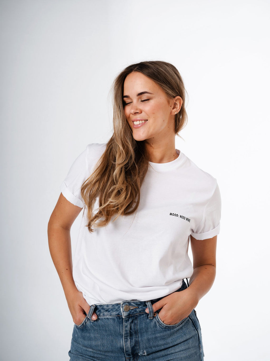 1. Women's white 'Mood: Need Wine' T-shirt by Black Giraffe Brand, worn by model with rolled-up sleeves, shown in lifestyle setting