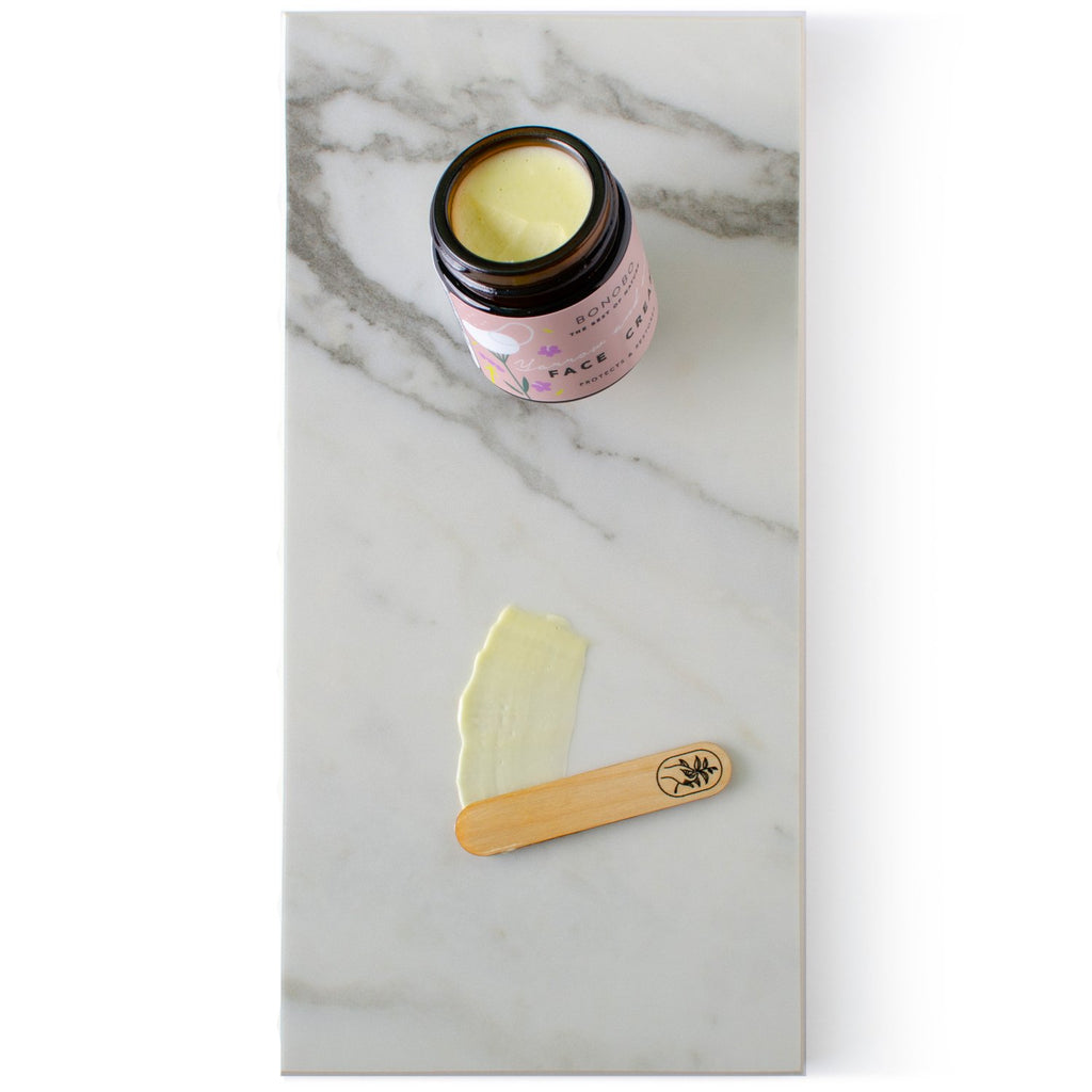 2. BONOBO Yarrow & Oregano Face Cream on marble with juniper spatula and cream swatch