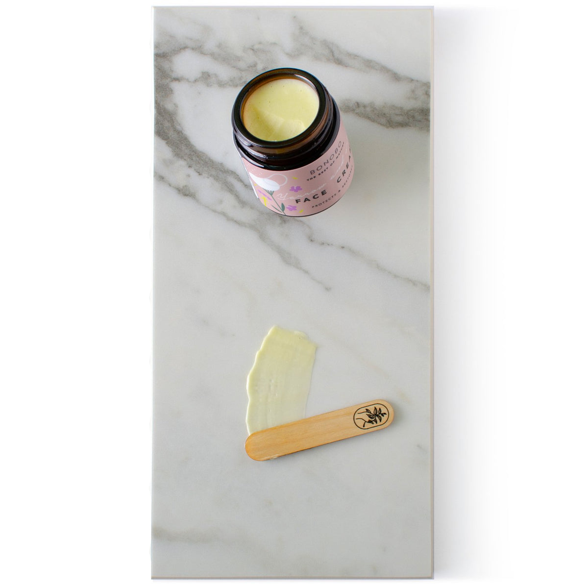 2. BONOBO Yarrow & Oregano Face Cream on marble with juniper spatula and cream swatch
