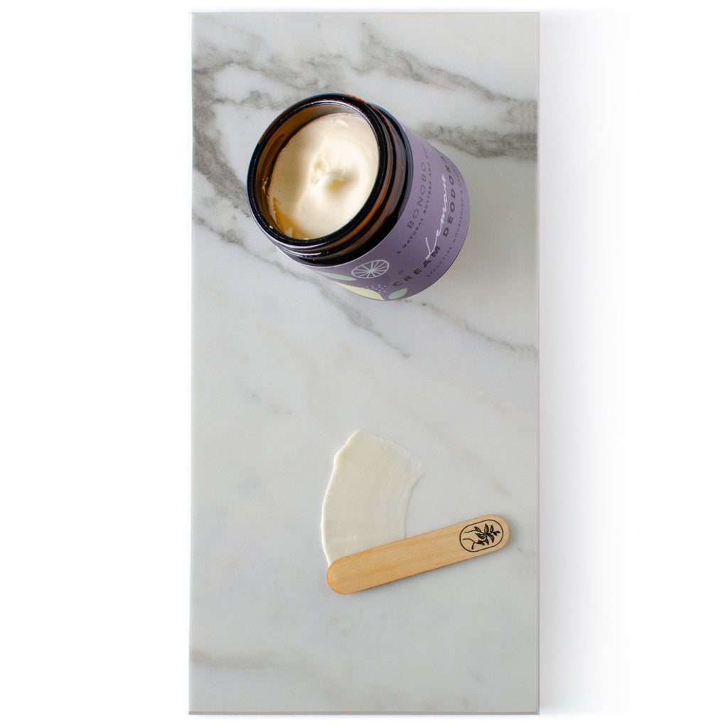 2. Open jar of BONOBO Lemon Deodorant-Cream with cream and applicator on marble surface