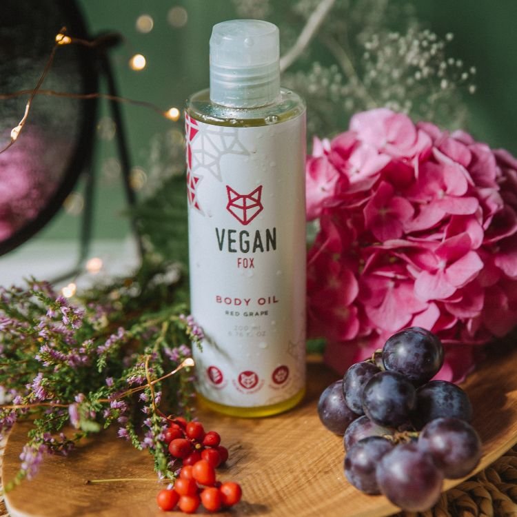 1. Vegan Fox Red Grape Body Oil, 200 ml, surrounded by flowers and grapes in a lifestyle setting