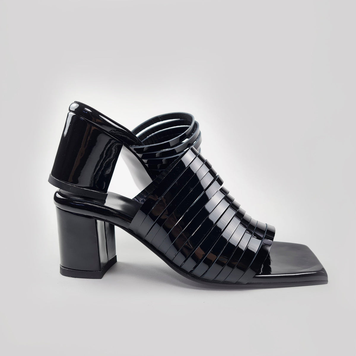 5. Side profile of women's black patent leather sandals with squared toe and block heel