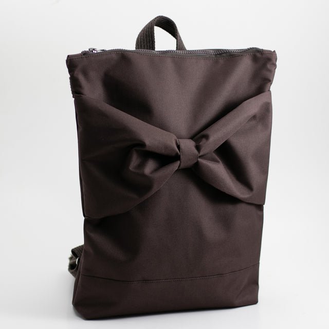 7. Studio shot of MUNI brown backpack with bow, showing adjustable straps and back design