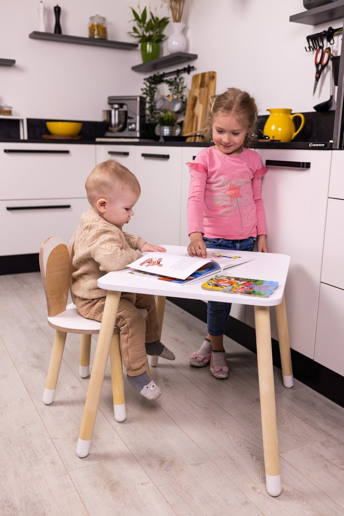 1. Two children using a white and natural wood bunny-themed table and chair set in a modern kitchen setting