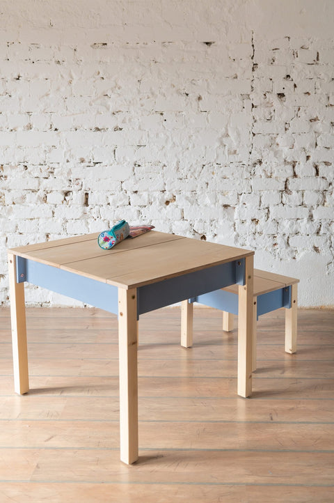 5. Blue and natural wood children's table and chair set with closed storage in a room with white brick wall