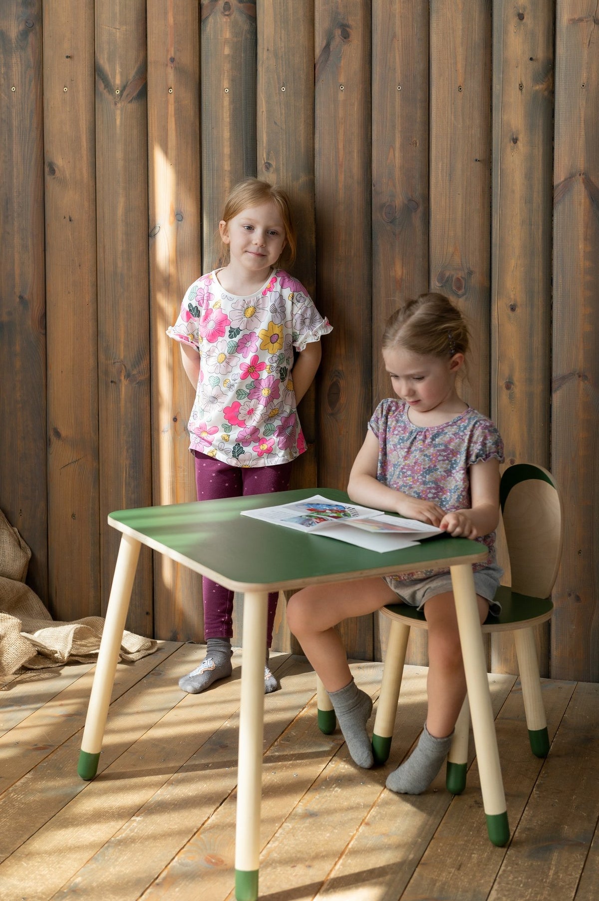 6. Two young girls with green bunny table and chair set in wooden room