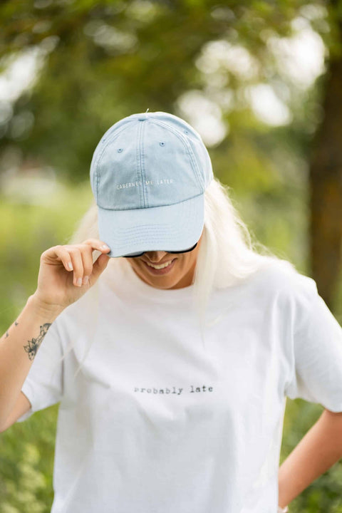 1. Woman wearing pastel blue cap with 'Cabernet Me Later' text, smiling in outdoor setting