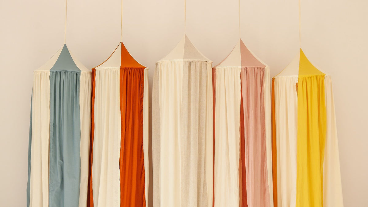 3. Row of colorful canopies in blue, orange, pink, and yellow hanging against a white wall